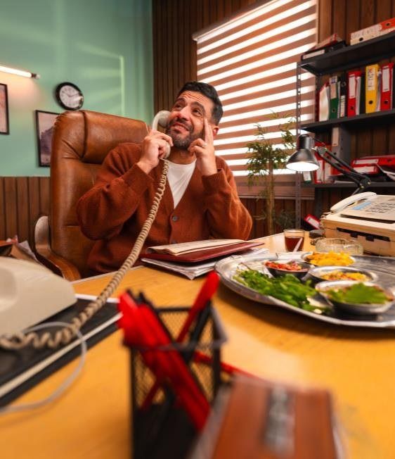 Islam Fawzy on a rotary phone at a cluttered desk