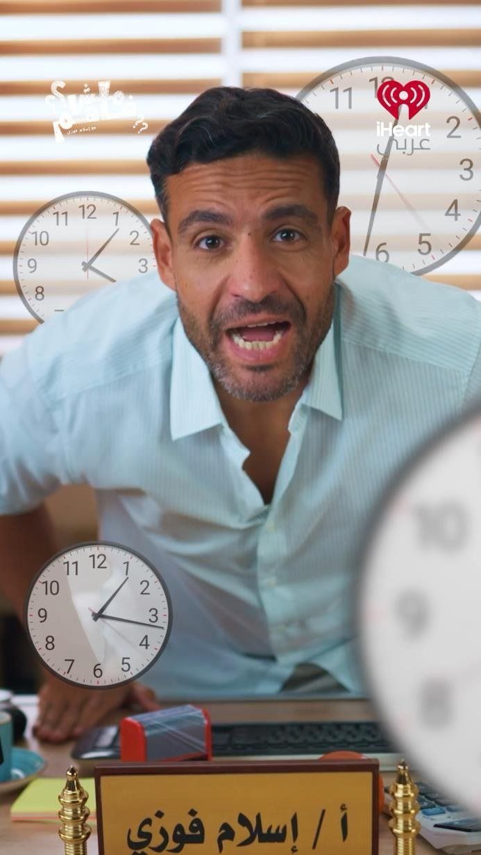 Islam Fawzy at a desk surrounded by clocks